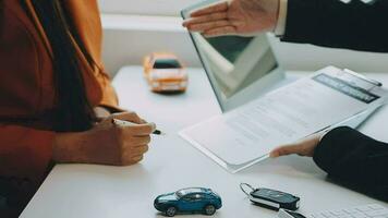 Salesman guiding customer seated at table Car business Dealership closing. and the new owner has entered into a contract video