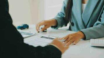 Salesman guiding customer seated at table Car business Dealership closing. and the new owner has entered into a contract video