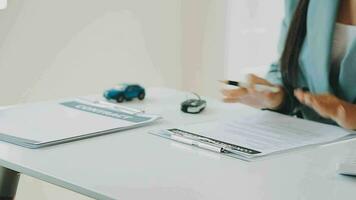 Salesman guiding customer seated at table Car business Dealership closing. and the new owner has entered into a contract video