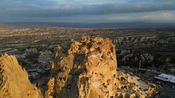 aéreo zumbido ver de el uchisar castillo en capadocia, Turquía durante puesta de sol. personas disfrutando el ver desde el parte superior de el castillo. video