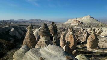 Aerial drone view of a person admiring the natural beauty of Pasabag Valley or Monks Valley and  Fairy Chimneys in Cappadocia, Turkey. Famous destination for hikers to explore the Rock Sites. video