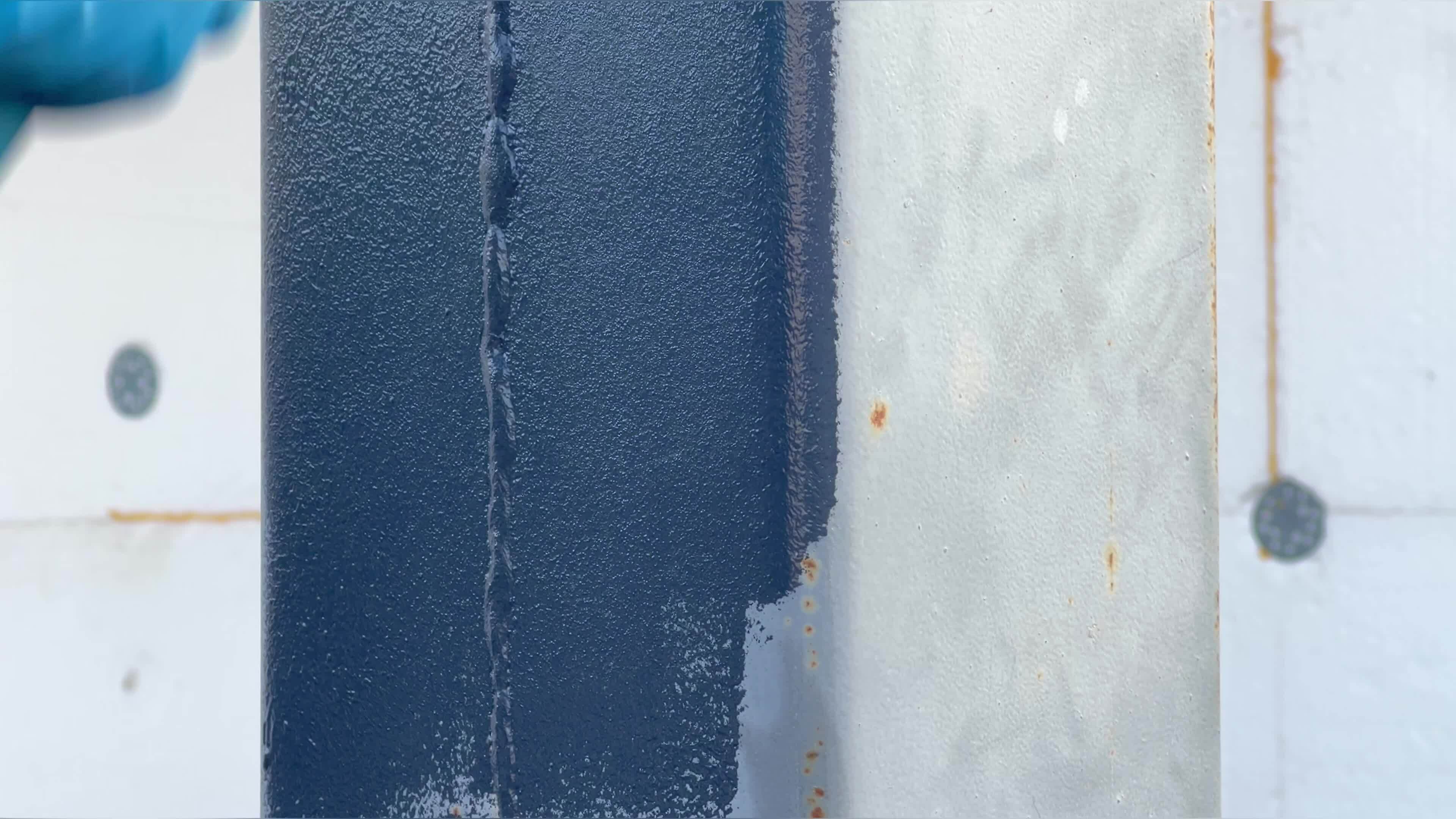 Paint a metal column gray with a roller brush by an artist in work