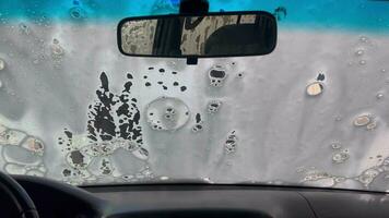 gotas de espuma correr abajo el vaso. jabón solución en el coche. textura de blanco espuma detergente en el lado ventana de un coche. hora a lavar el coche. video