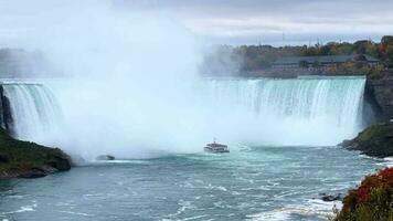 de imponerande skala av niagara faller. en båt med turister längs de flod till de vattenfall. en kraftfull vatten element. en hisnande syn, en unik naturlig parkera. video