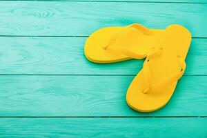 Yellow flip flops on blue wooden background. Summer holidays. Top view. Mock up. Copy space photo
