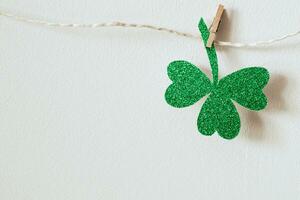 Happy St. Patricks day. Green glitter shamrocks decoration. Shiny paper cut clover leaf on clothespin photo