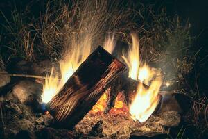 Bright night bonfire among grass and stones. Beautiful bonfire with flying sparks pattern photo