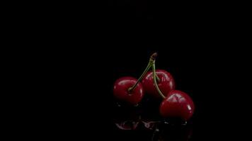 Cerise lent mouvement fermer chute dans l'eau avec éclaboussure gouttelettes sur noir Contexte macro coup cuisine vidéo video