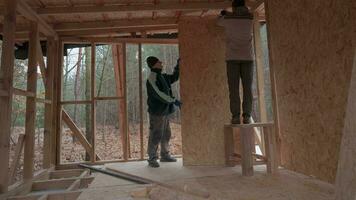 Time lapse of workers build a wooden frame house. Carpenters mount OSB wooden panel on the wall of the future cottage. The concept of carpentry and construction work. video