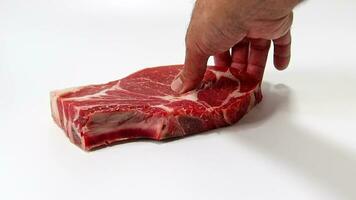 A hand picking up a beef steak, isolated on a white background. Slow motion. video