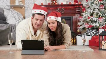 couple mensonge sur le sol dans Noël veille achats en ligne en utilisant une tablette pc. magnifique orné arbre dans le Contexte video