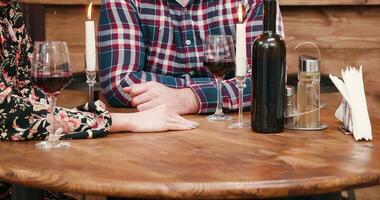 nehmen Hand von ein geliebt Person. schließen oben Aufnahmen im Jahrgang Restaurant. Dort ist ein Flasche von Wein auf das Tabelle und zündete Kerzen video