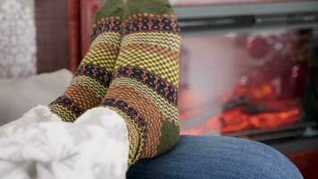 Woman feet in warm woollen socks next to a burning fireplace. Cozy home video