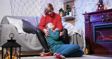 Cheerful mother tickles her daughter on christmas day waiting for santa with gifts. video