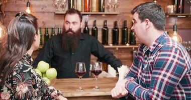 magnifique caucasien couple en buvant du vin à le bar compteur et parlant avec une barbu branché barman video