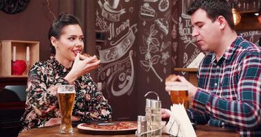 linda casal é bebendo Cerveja e comendo pizza dentro vintage bar ou restaurante. uma barbudo barman é trabalhando dentro a fundo video