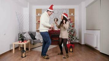 Beautiful happy couple with champagne glasses in hands dancing and having fun in Christmas evem, slow motion wide shot video