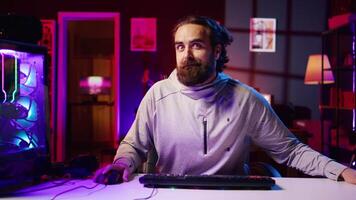 Happy content creator in neon lit studio interacting with audience during livestream, making silly faces to make viewers laugh. Funny gamer engaging in shenanigans while streaming, entertaining fans video