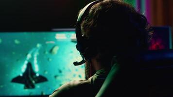 man spelar uppkopplad multiplayer rymdskepp TV-spel med vänner, använder sig av hörlurar för uppslukande erfarenhet. spelare använder sig av gaming uppstart till flygande rymdskepp i flyg spel, njuter fritid tid video