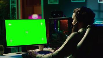 Player having fun by using isolated screen computer monitor to play singleplayer videogame. Professional gamer using chroma key PC desktop to complete levels in game, talking with friends video