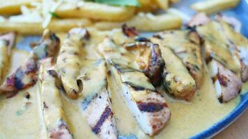 redo till äta skivad kyckling med grädde sås med franska frites på en tallrik . video