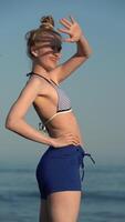 Portrait sensual woman raised hand to forehead, posing and looking away, standing on beach video