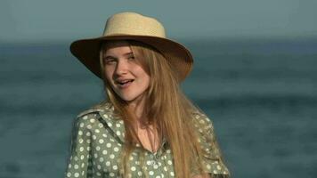 Happy young blonde woman smiling and looking at camera. Female in straw hat, green polka dot dress video