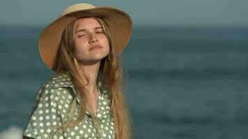 jong blond vrouw draaien hoofd, op zoek in de omgeving van, past zich aan rietje hoed, covers gezicht van zon met palm video
