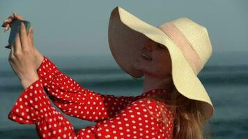lycka kvinna använder sig av smartphone, framställning video selfie till fångande stunder från resa till strand