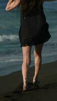 Rear view of unrecognizable woman with long legs running along beach of black sand of Pacific Ocean video