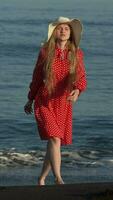 Front view of barefoot woman model walking on black sands beach of Pacific Coast. Slow motion video