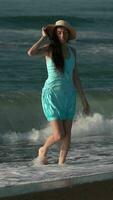 Caucasian barefoot woman walking on sandy beach in breaking waves and splashes during beach holidays video