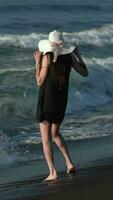 Full length unrecognizable barefoot woman standing on black sandy beach on Pacific Ocean video