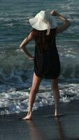 Playful barefoot woman standing in breaking waves and splashes on beach during summer beach holidays video