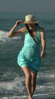 Sensual woman walking along beach, smiling and looking at camera. Female in short dress, sun hat video