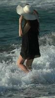 Caucasian barefoot woman in breaking waves and splashes on beach during summer beach holidays video
