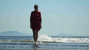 sensualidad mujer camina en playa durante verano día. lleno longitud modelo en rojo polca punto Picardias vestir video