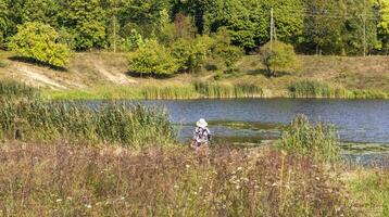 Shot of the senior lady fishing in the pond. Concept photo