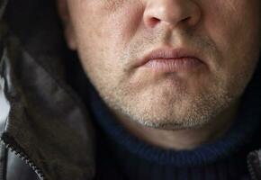 Portrait of the mid aged man with grey hair, wearing warm, dark blue sweater and grey coat. People photo