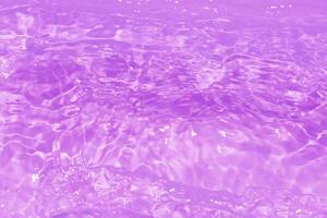 Purple water waves on the surface ripples blur. Defocus blurred transparent pink colored clear calm water surface texture with splash and bubbles. Water waves with shining pattern texture background. photo