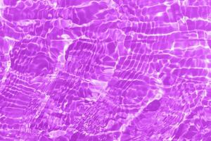 Purple water waves on the surface ripples blur. Defocus blurred transparent pink colored clear calm water surface texture with splash and bubbles. Water waves with shining pattern texture background. photo