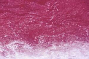 Purple water waves on the surface ripples blur. Defocus blurred transparent pink colored clear calm water surface texture with splash and bubbles. Water waves with shining pattern texture background. photo
