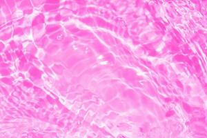 Purple water waves on the surface ripples blur. Defocus blurred transparent pink colored clear calm water surface texture with splash and bubbles. Water waves with shining pattern texture background. photo