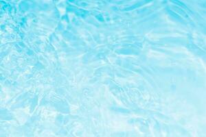 Bluewater waves on the surface ripples blurred. Defocus blurred transparent blue colored clear calm water surface texture with splash and bubbles. Water waves with shining pattern texture background. photo