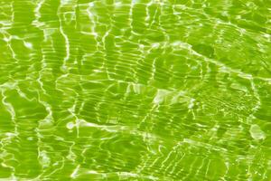 Green water waves on the surface ripple blurred. Defocus blurred transparent blue colored clear calm water surface texture with splash and bubbles. Water waves with shining pattern texture background. photo