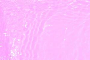 Purple water splashes on the surface ripple blur. Defocus blurred transparent pink colored clear calm water surface texture with splash and bubble. Water waves with shining pattern texture background. photo