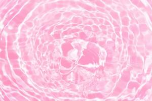 Purple water splashes on the surface ripple blur. Defocus blurred transparent pink colored clear calm water surface texture with splash and bubble. Water waves with shining pattern texture background. photo