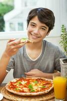 contento adolescente chico comiendo Pizza foto