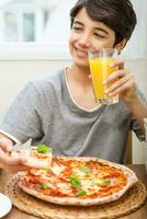 adolescente chico disfrutando Pizza y jugo foto