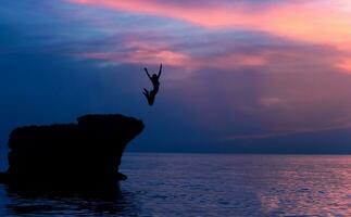 Brave girl jumping from rocks photo